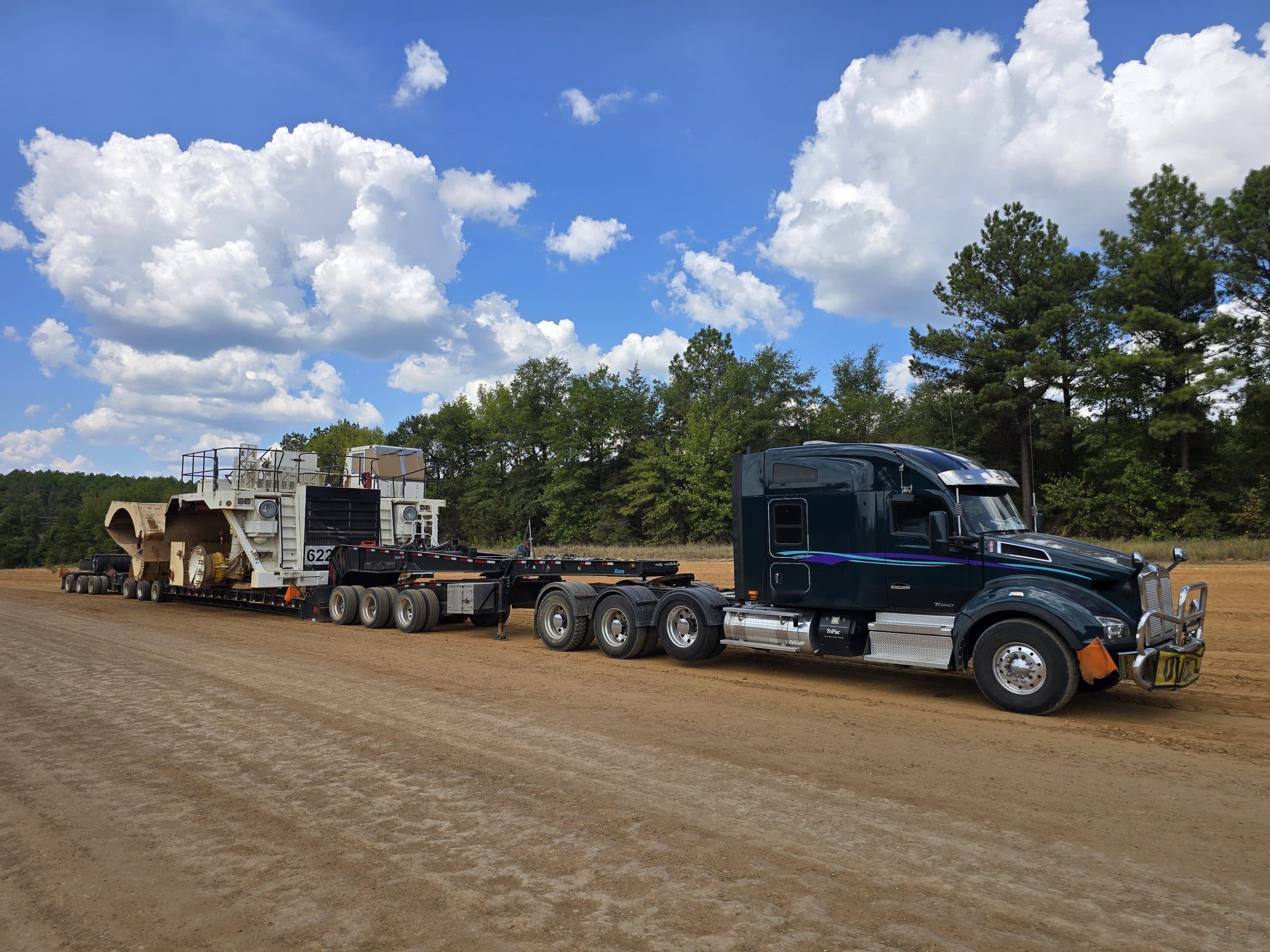 The XL 140 HDE combination from the side, hauling a mining haul-truck chassis on a dirt site road
